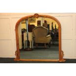 A pine overmantel mirror in arched frame with carved shell surmount, 134cm wide, 117cm high