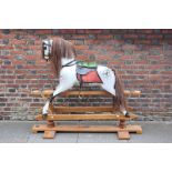 A Stevenson Brothers rocking horse in dapple grey with saddle, on brass rocking mounts and oak