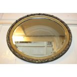 An oval gilt framed wall mirror with scrolling floral and foliate composite frame, mirror plate 41.