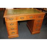 An early 20th century oak pedestal desk with green leather inset top (a/f), and nine drawers, on
