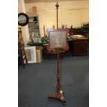 A Victorian mahogany adjustable fire screen with floral needlework panel in glazed frame, on