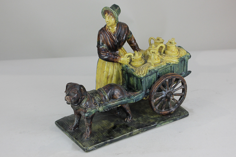 A 19th century Continental pottery group, possibly German, of a milkmaid with dog and milk cart,