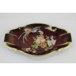 A Carltonware porcelain dish depicting a bird of paradise and flowering tree on Rouge Royale ground,