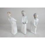 Three Lladro porcelain figures of children in nightgowns, one holding a candle, the other two