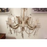 A modern glass chandelier with eight scroll branches, central baluster stem, swags and drops,