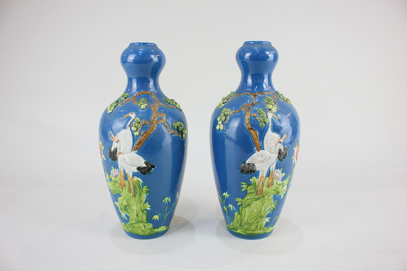 A pair of Chinese pottery vases depicting storks under a tree, on blue ground, seal mark to base,