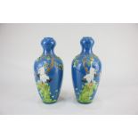 A pair of Chinese pottery vases depicting storks under a tree, on blue ground, seal mark to base,