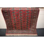 A Bokhara rug with red ground and three rows of elephant foot motifs within multiguard border, 125cm