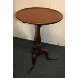 A Georgian mahogany tilt-top table with circular dished top on baluster turned stem and outswept