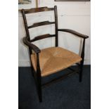 An oak ladder back low armchair with rush seat