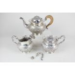 A Chinese white metal three piece tea set, circular shape embossed with birds amongst blossoming