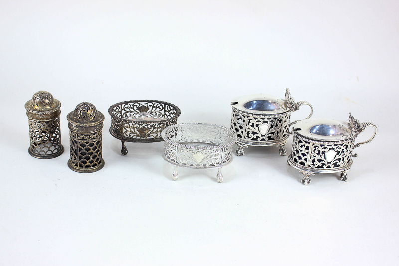 A George V silver six piece cruet set, oval form with pierced decoration, on claw and ball feet (two