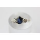 A sapphire and diamond three stone ring, claw set with an oval cut sapphire and two brilliant cut