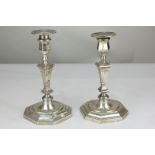 A pair of George V silver candlesticks with urn shaped sconces on baluster stems and loaded