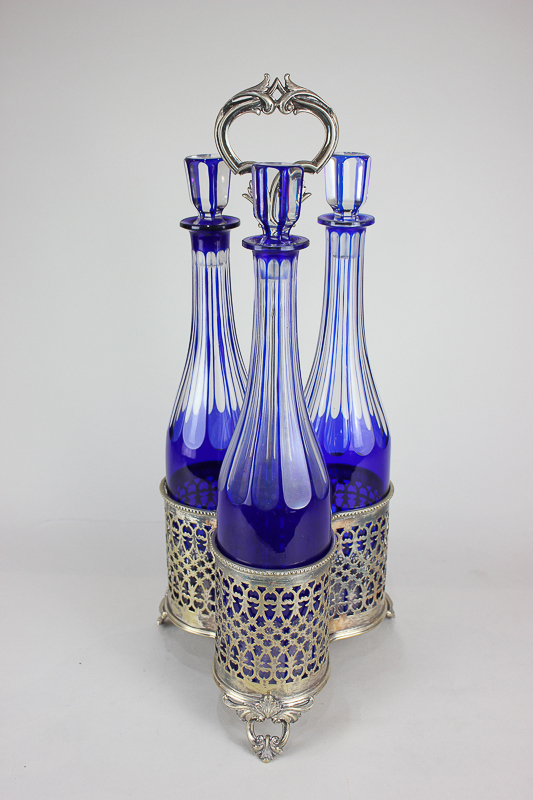 A silver plated three-bottle cruet stand with pierced design and scroll handle, the three cut