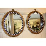 A pair of George III style oval wall mirrors, each with white and blue coloured glass border, within