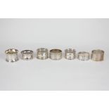 A collection of seven various silver napkin rings, various styles and dates, two with engraved