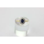 A sapphire and diamond cluster ring, the oval cut stone in a border of ten brilliant cut diamonds in