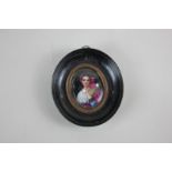 An oval miniature portrait of a lady in European dress, wearing a pink headscarf, one hand raised to