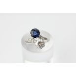 A good diamond and sapphire two stone crossover ring, the circular cut stones multi-claw set with