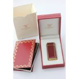 Les Must de Cartier, a red lacquer and rolled gold cigarette lighter, in case with papers