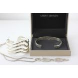 Georg Jensen, a silver bangle in case, engraved with initials M-R, D-H, a Joaquim Berao white