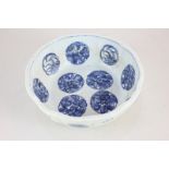 A Chinese pottery blue and white bowl decorated with circular floral panels, 19.5cm diameter