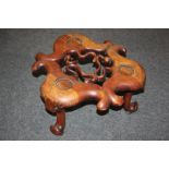 A Chinese rosewood pot stand with carved top and central pierced decoration, on three short legs,
