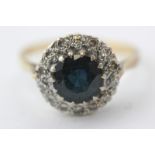 A sapphire and diamond cluster ring, the circular stone multi-claw set within a border of fourteen