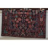 A Persian pattern wool rug, the central motif surrounded by geometric floral shapes and borders, red