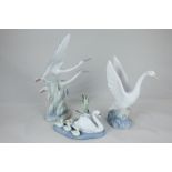 A Lladro porcelain model of a swan with young, 15cm, a Nao figure group of two flying storks, and