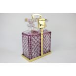 A two-bottle purple and clear glass spirit decanter tantalus with gilt metal frame and lock with