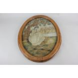 A 19th century oval silk needlework depicting a woman seated under a tree, beside a river, with a