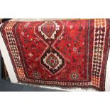 A Persian style wool rug, red field, with three diamond lozenge centre, and cream patterned