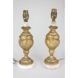 A pair of gilt painted baluster table lamps decorated in raised relief with putti and scrolling