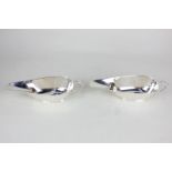 A pair of George VI silver sauce boats with scroll handles on reeded bases, engraved initials and