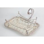 An Edward VII silver asparagus stand and trivet of concave rectangular form with scroll handle,