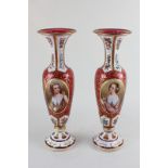 A pair of 19th century Bohemian cranberry glass baluster vases, each with enamelled portrait panel