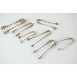 Seven George V silver sugar tongs with claw grips, makers including Robert Pringle & Sons,