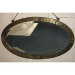 A hammered brass oval wall mirror, with bevelled glass, 48cm by 81cm