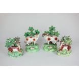 A pair of Staffordshire pottery sheep, a ewe and a ram, both with a lamb and bocage foliage,