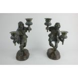 A pair of bronze figural two-branch candlesticks in the form of men holding aloft a candle socket in