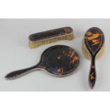 A George V silver mounted tortoiseshell dressing table set of hand mirror and two brushes,