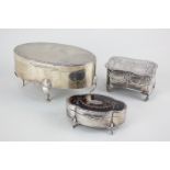 An Edward VII silver oval dressing table box with fitted cloth interior, on four cabriole feet,
