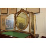 A giltwood framed three-panel dressing table mirror with floral surmount and central oval panel,