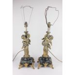 A pair of Louis XV style gilt table lamps in the form of putti seated on columns, on Verde Antico