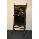 A Regency mahogany cheval mirror, the rectangular plate in a ring turned support, on outswept