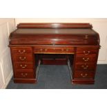 A Victorian mahogany roll-top desk with tambour top enclosing pigeon holes and drawer, above two