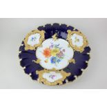 A Meissen style porcelain shallow bowl, the scalloped border with gilt embellishments on dark blue