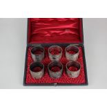 A cased set of six silver plated napkin rings cast with scroll decoration and frilly border, in